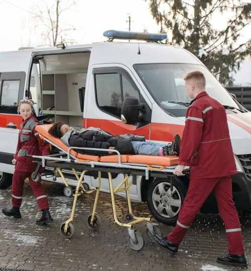 Paramedics transferring a patient on a stretcher to an ambulance for emergency care.